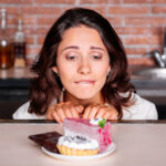 Woman craving piece of cake on a plate