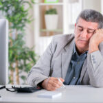 exhausted man sitting in front of computer