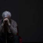 Older man sits alone, appearing depressed