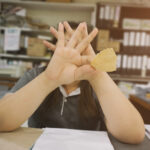 woman eating chips covering her face