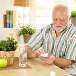 Man taking pill at kitchen table