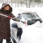 Woman scraping snow off of her car