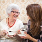 Senior woman drinking coffee with grand-daughter