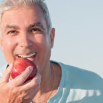 Happy older man eating an apple