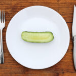 Half a cucumber on a plate with knife and fork