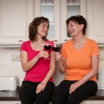 Senior mom and adult daughter drinking red wine together