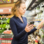 Young woman comparing produce at grocery store