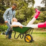 Smiling man pushing laughing woman in wheelbarrow